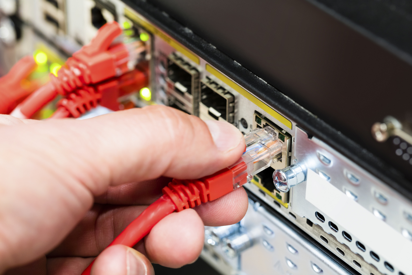Hand Plugging Network Cable Into Switch In Datacenter